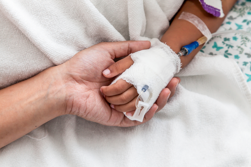 mother holding child's hand who have IV solution