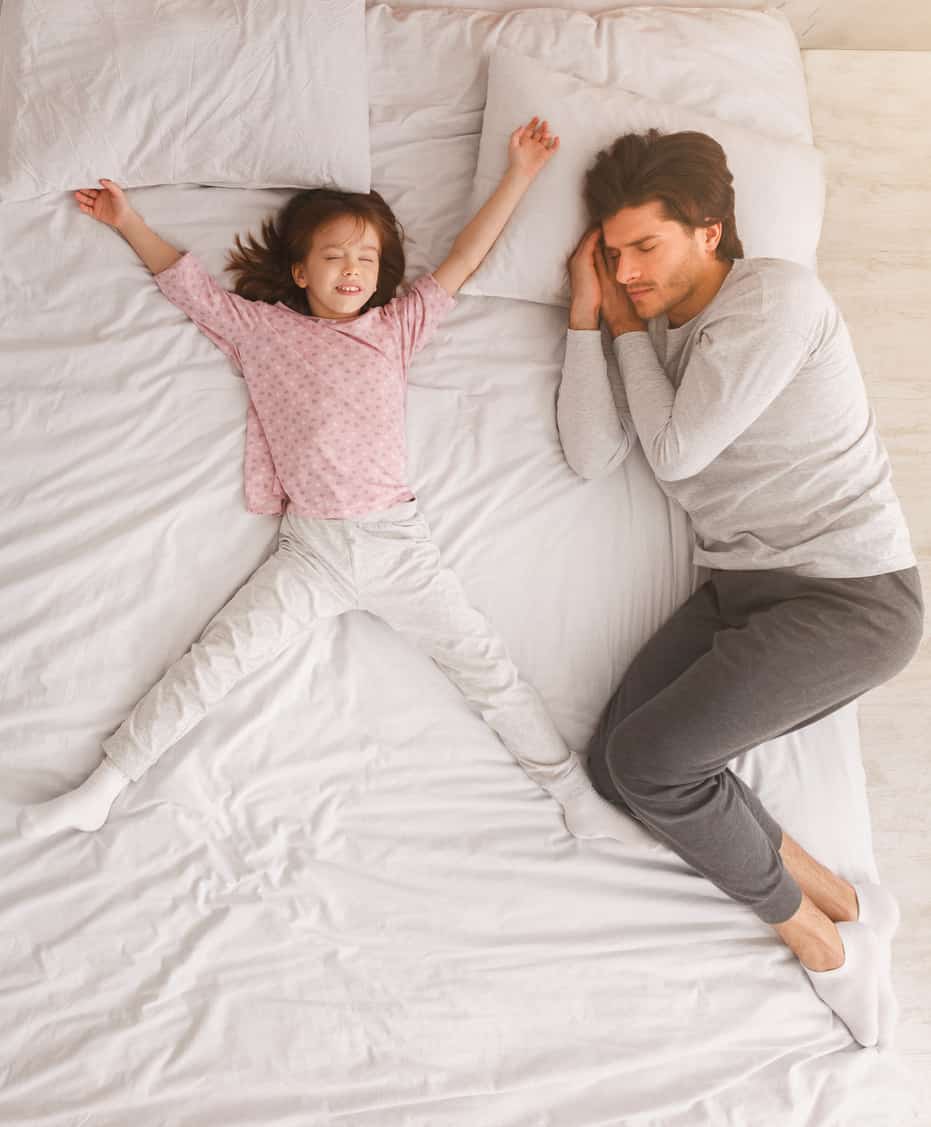 Dad and little girl sleeping together on bed