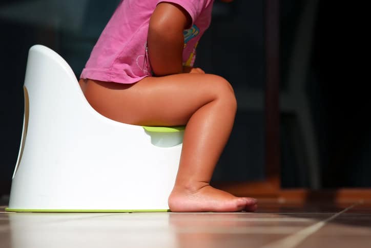 Children’s legs hanging down from a chamber-pot